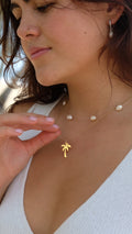 Woman wearing a gold Palm Cove necklace