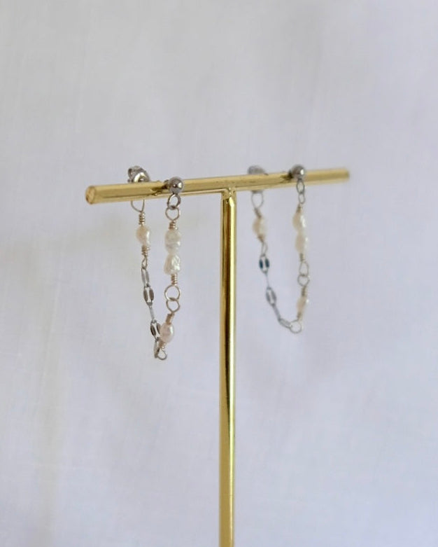 Gold jewelry stand featuring the Pearl earrings with a white background