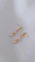 Pair of earrings with pink and gold beads on a light gray background