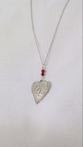 Silver heart-shaped pendant necklace on a white background